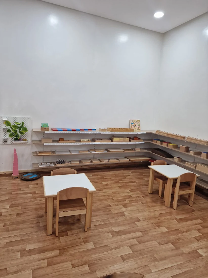 Salle de classe Montessori avec tables et étagères